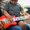 BABY EINSTEIN Hračka drevená hudobná gitara Together in Tune Guitar™ Connected Magic Touch™ HAPE 6m+